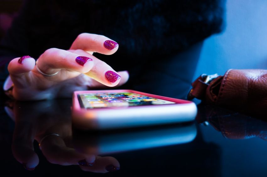 Apps - person using black smartphone with gray and pink case