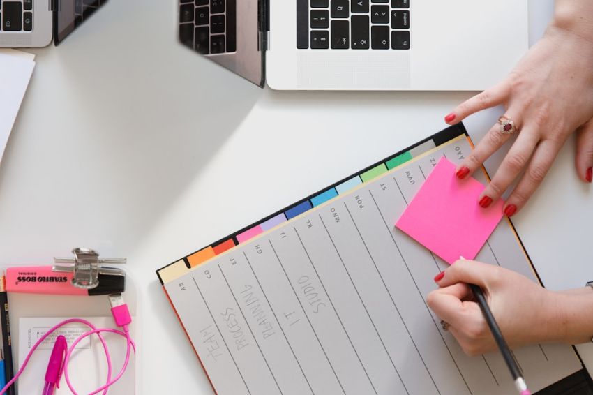 Planning - person holding pencil and stick note beside table