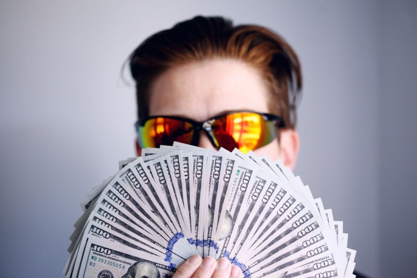 Benefits - man in black framed sunglasses holding fan of white and gray striped cards