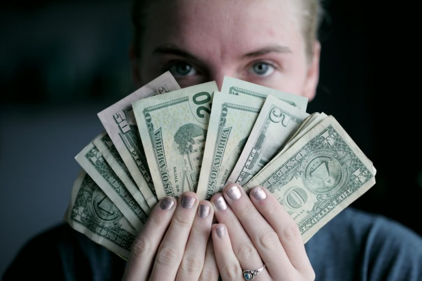 Wages - person holding fan of U.S. dollars banknote