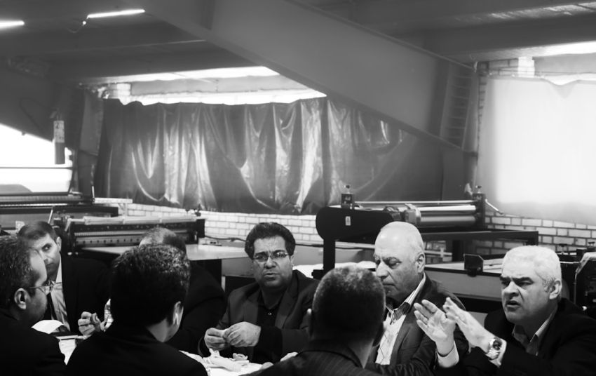 Negotiating - grayscale photography of group of person sitting indoors