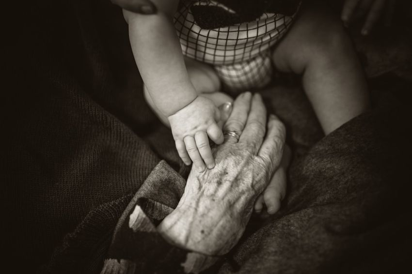 Age - an older woman holding a baby's hand