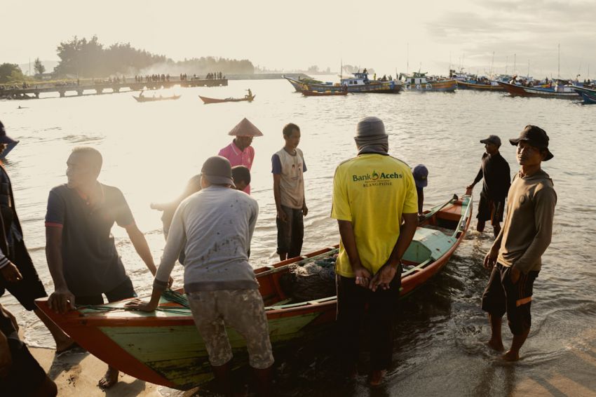 Loan Offers - a group of people standing around a boat in the water