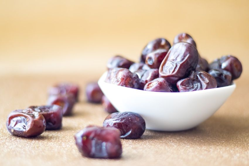 Dates - brown round fruit on white ceramic bowl