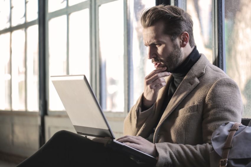 Benefits - man holding his chin facing laptop computer