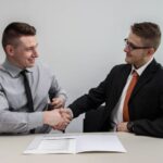 Benefits - two men facing each other while shake hands and smiling